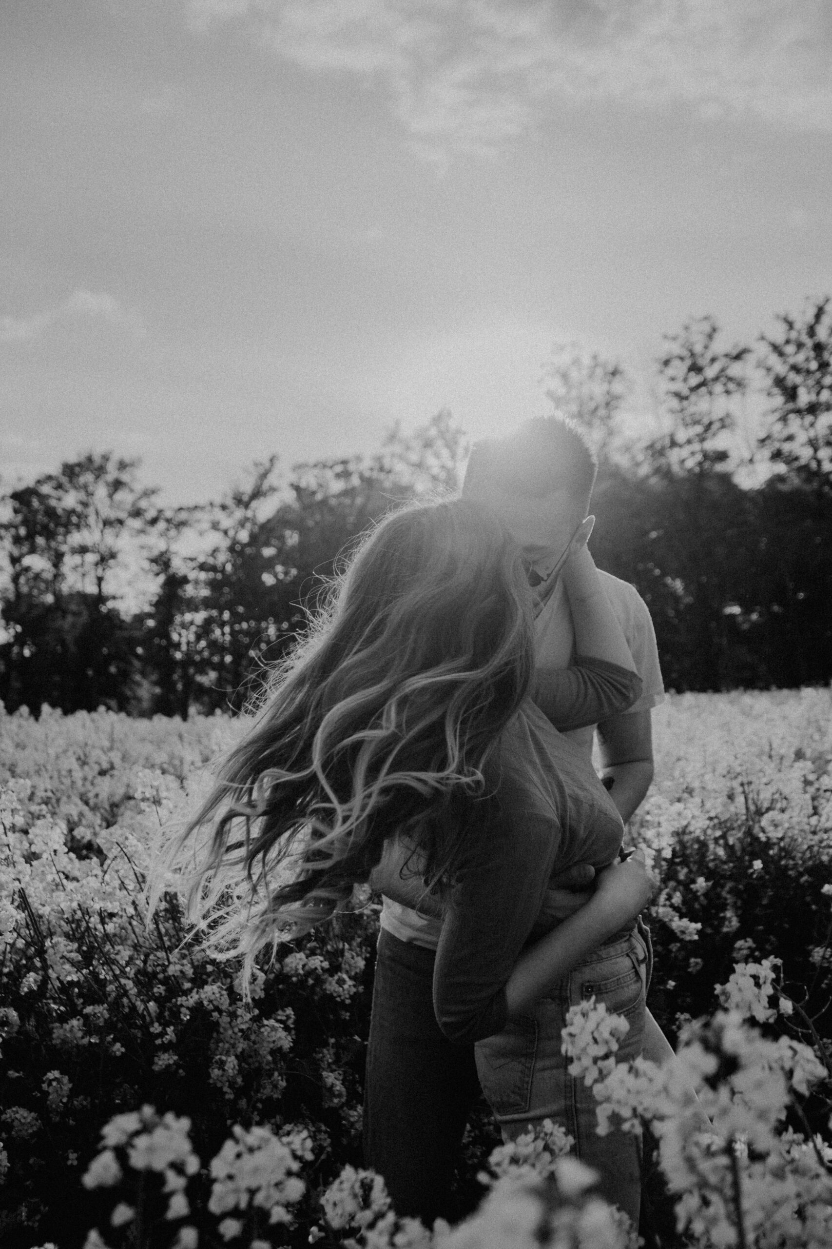 Verliebtes Paar umarmt sich im Gegenlicht in einem Blumenfeld – Liebe und Beziehungen ab 40